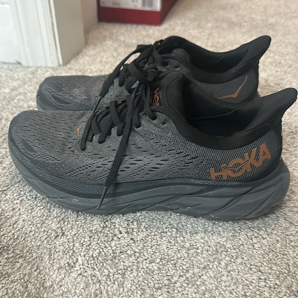 HOKA
Black w bronze symbol 
Clifton